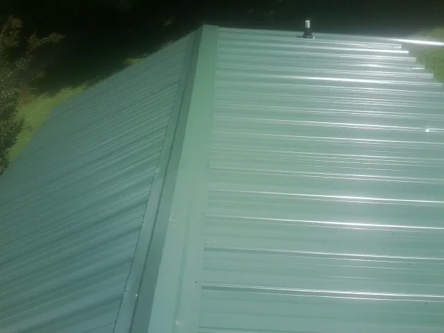 New green metal panels meeting at the ridge of a roof — Flat Roof Repair work by our crew in Columbus